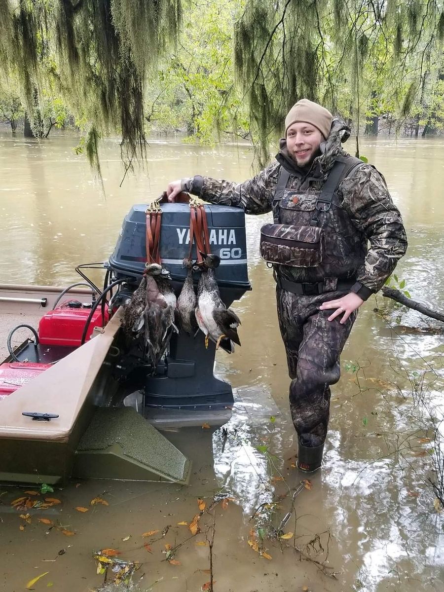Guide beside the jon boat with ducks at the ready