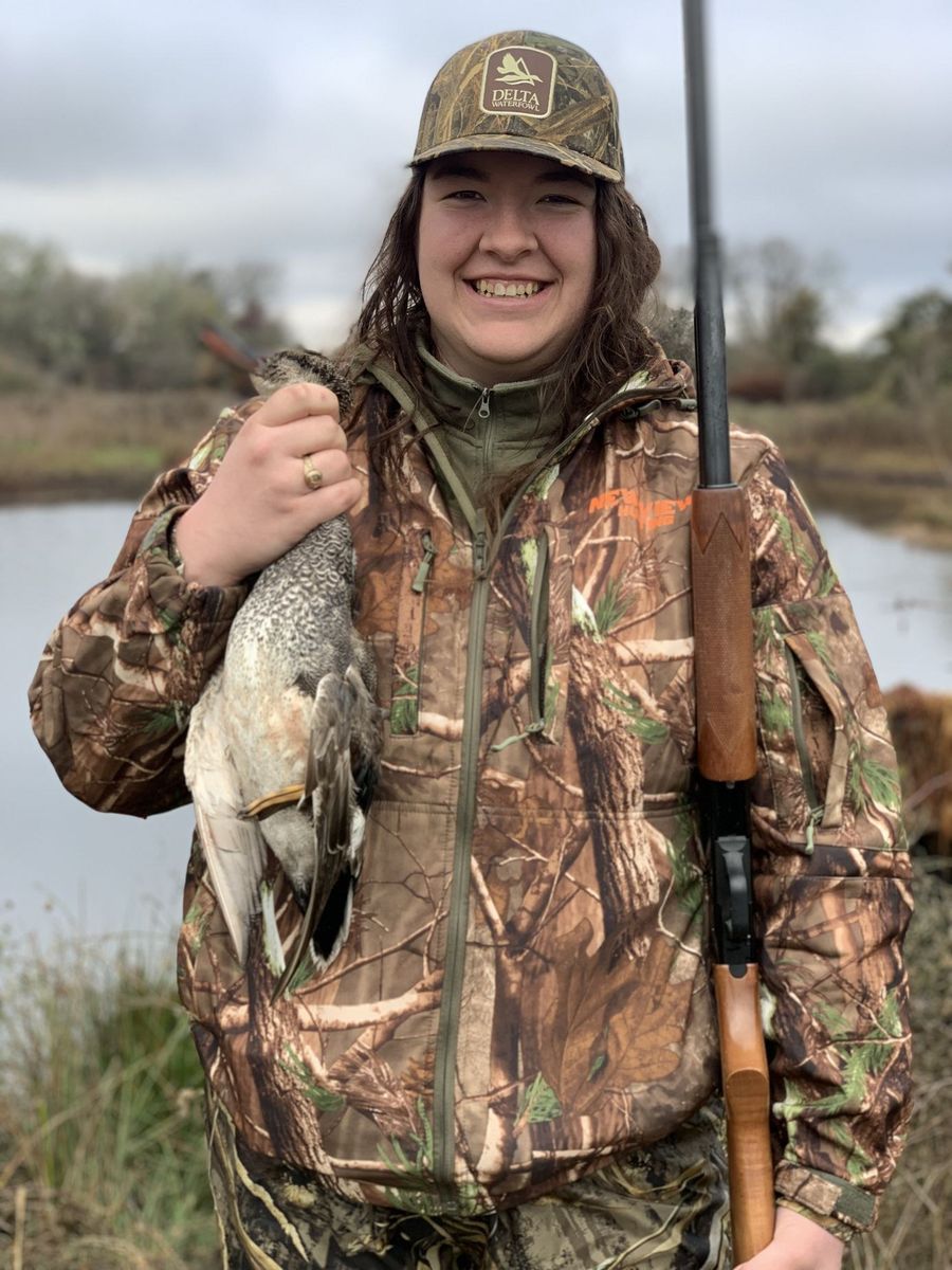 A hunter smiling with her bird after a morning in the marsh
